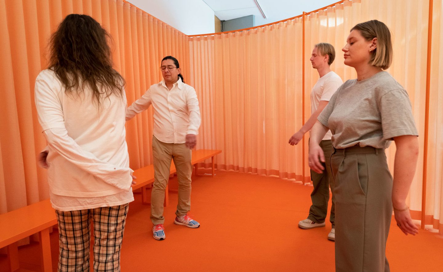 Four people swinging their arms in one of Jeppe Hein's chakra rooms