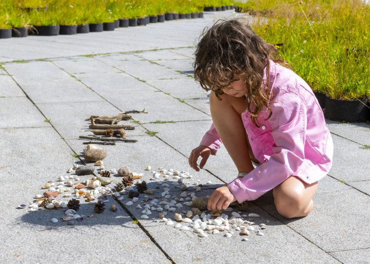 A girl is sitting on the ground, playing with gravel