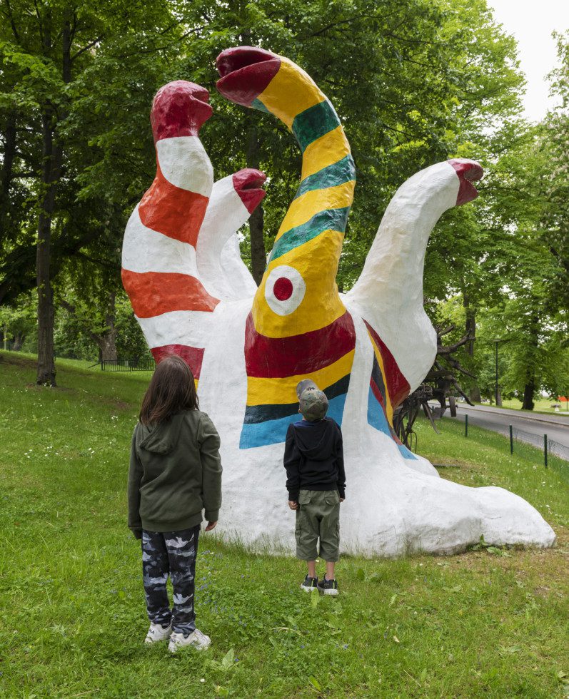 Children looking at a piece from the installation "Le Paradis fantastique", standing in the grass