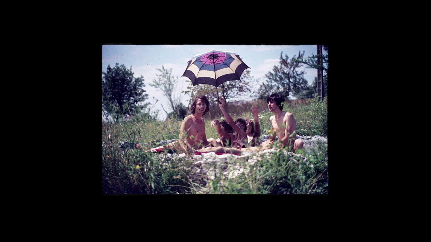 People sitting in the grass on a sunny day with umbrella