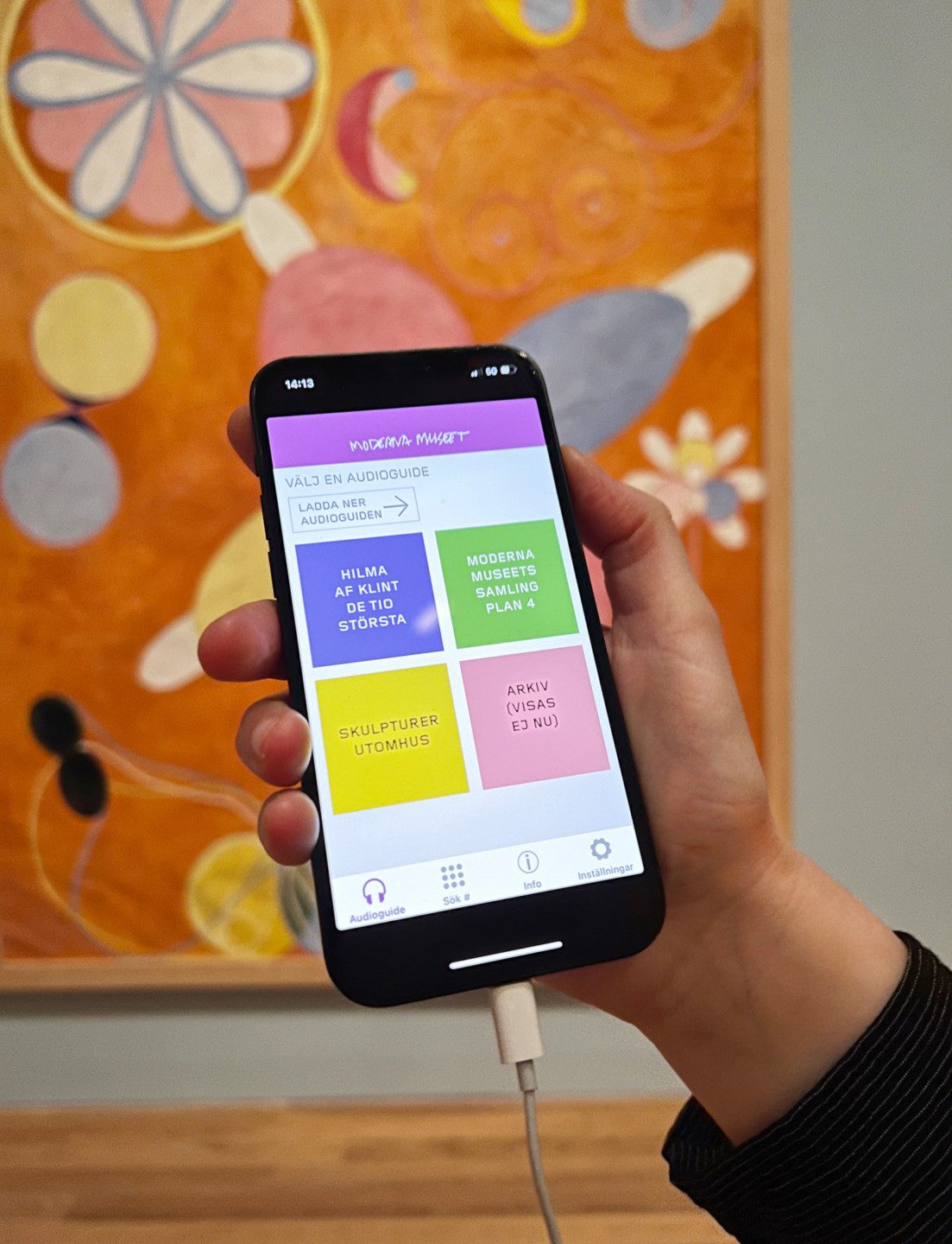 En hand som håller i en mobiltelefon där audioguiden visas
