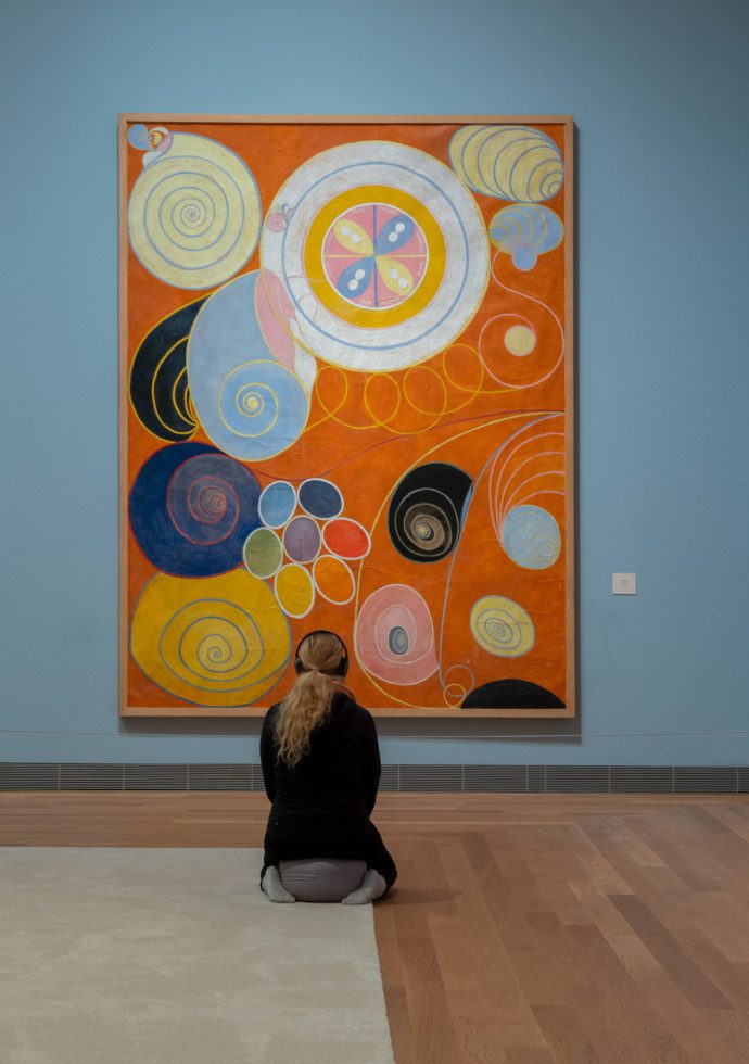 A person in front of the painting Yngligaåldern  no3 by Hilma af Klint
