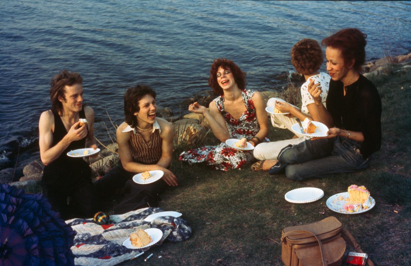 A group sits next to water and has a picnic