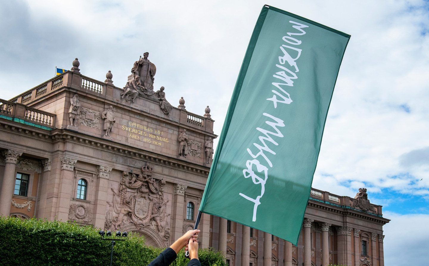 A Moderna Museet flag in front of Sweden's Riksdag