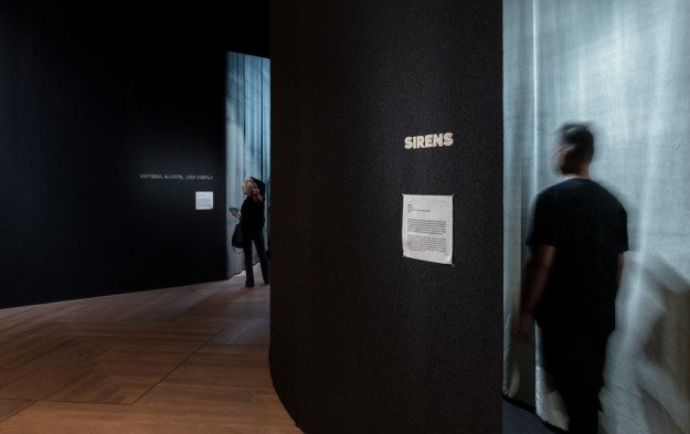 A person entering one of the rooms included in "Nan Goldin – This Will Not End Well". Another person stands further back in the picture and looks at a work text