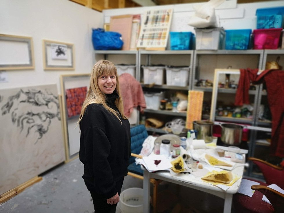 The artist Sigrid Holmwood is standing in her studio.