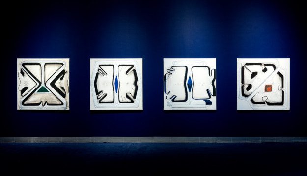 Fyra abstrakta konstverk på en mörkblå vägg