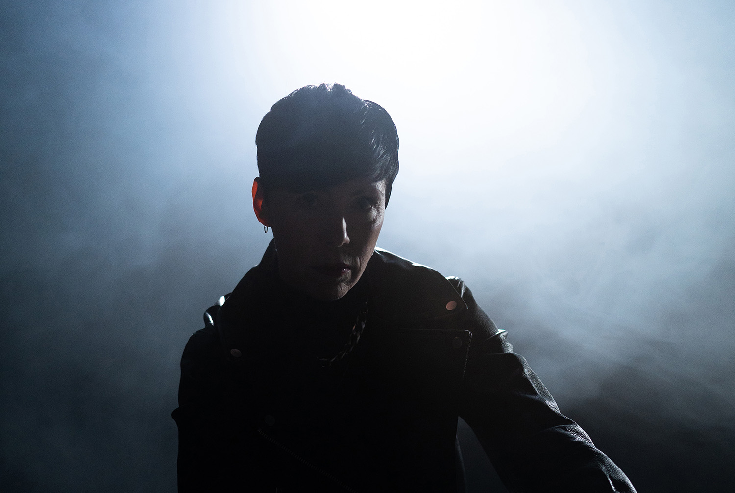 The artist EMMON poses in front of a spotlight