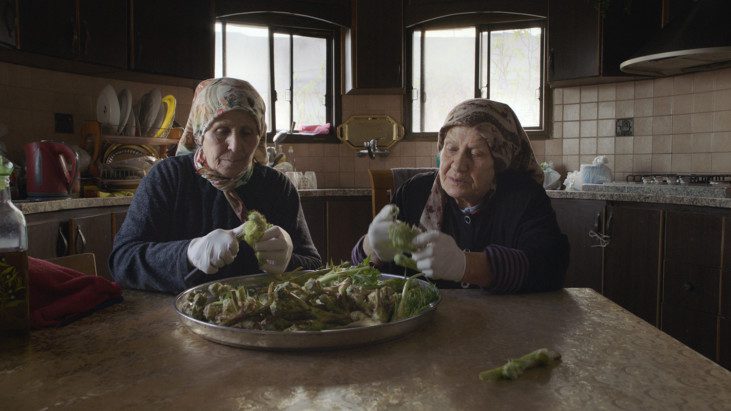Två äldre kvinnor sitter vid ett bord och rensar örter