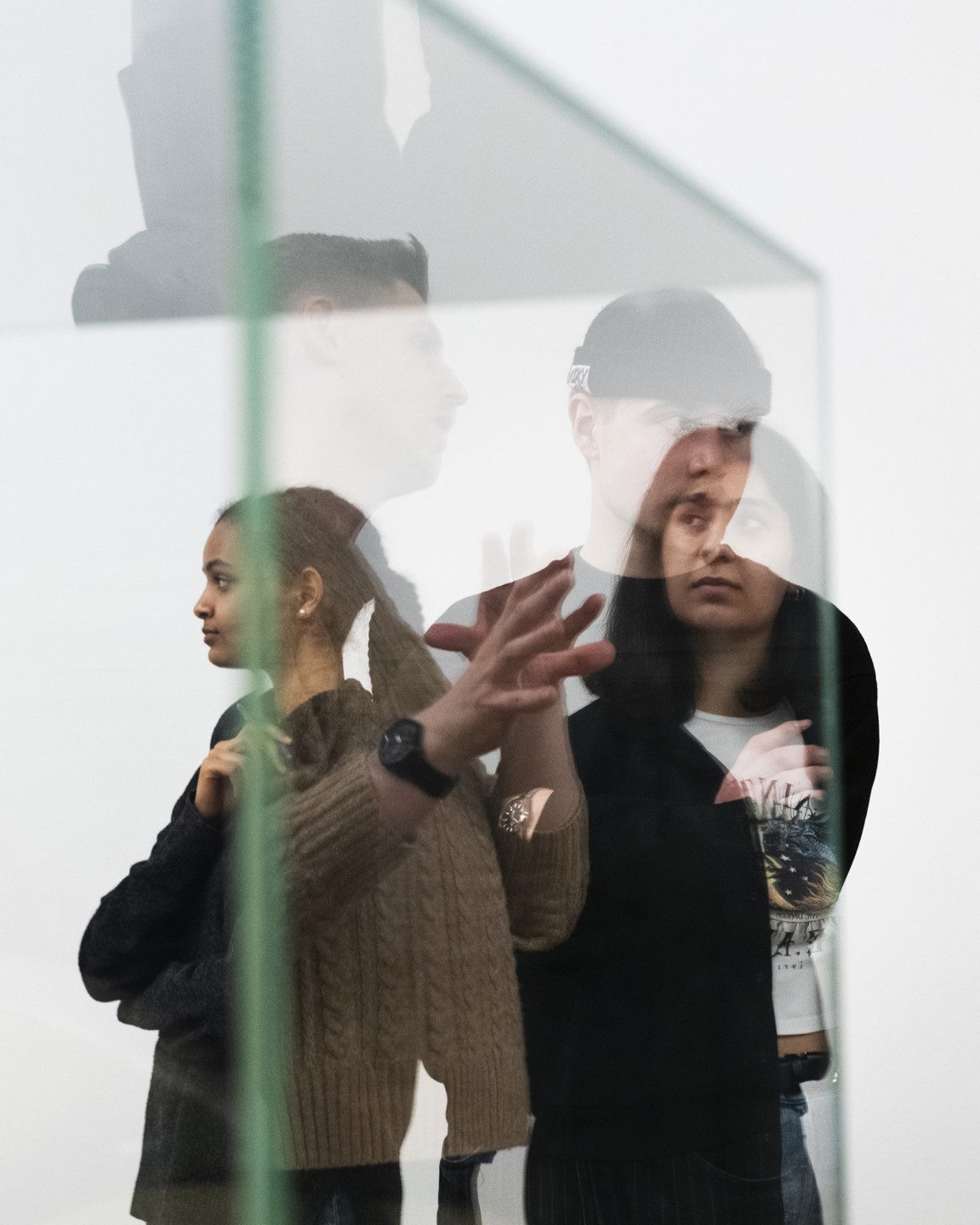 Three people photographed through a glass case