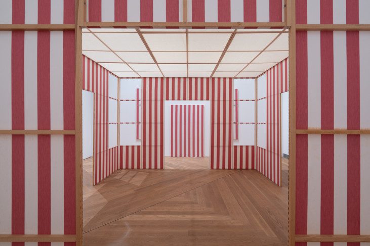 A semi-open space with walls made out of pink and white fabric fastened between wooden frames
