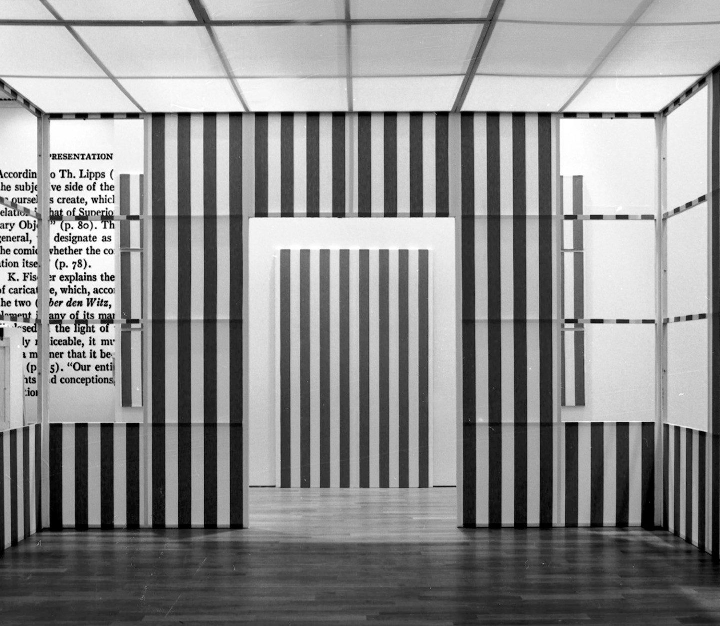 A black and white photo of a semi-open space with walls made out of pink and white fabric fastened between wooden frames