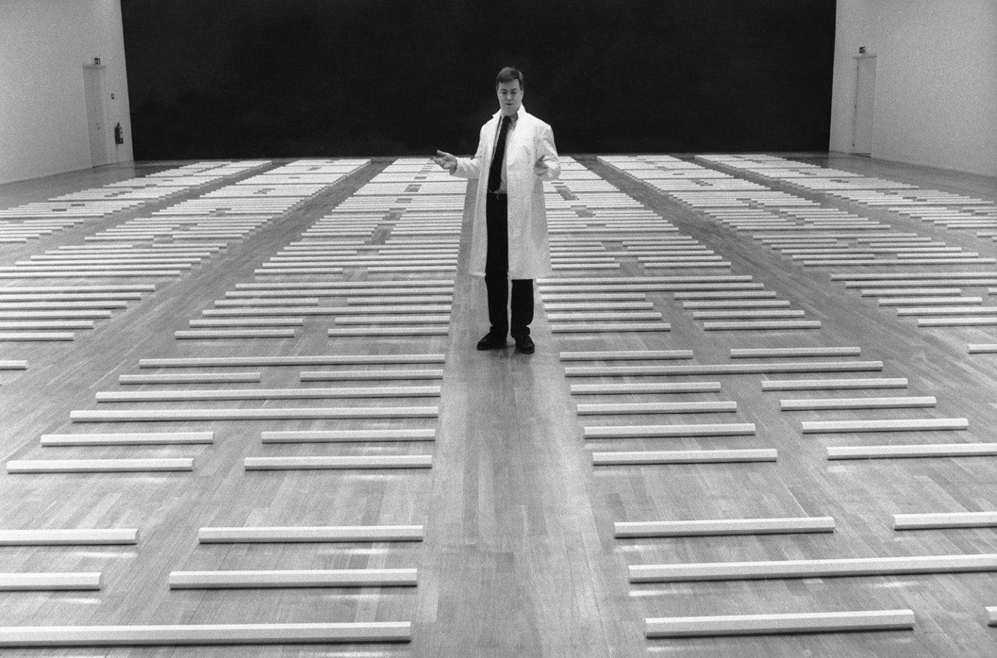 A black and white photo of a man (Lars Nittve) standing in the middle of the floor in the installation "I Ching"