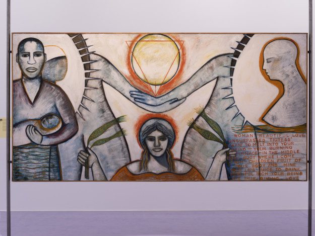 Photo of the painting "Woman Beautiful Love/Tigress". The painting shows three figures, one of which holds a child, one holds green plants in both hands, and one is seen in profile. Two bodies holding hands are seen behind two radiant circles. At the top center of the painting is a yellow sun with an upside down triangle on top of it. 