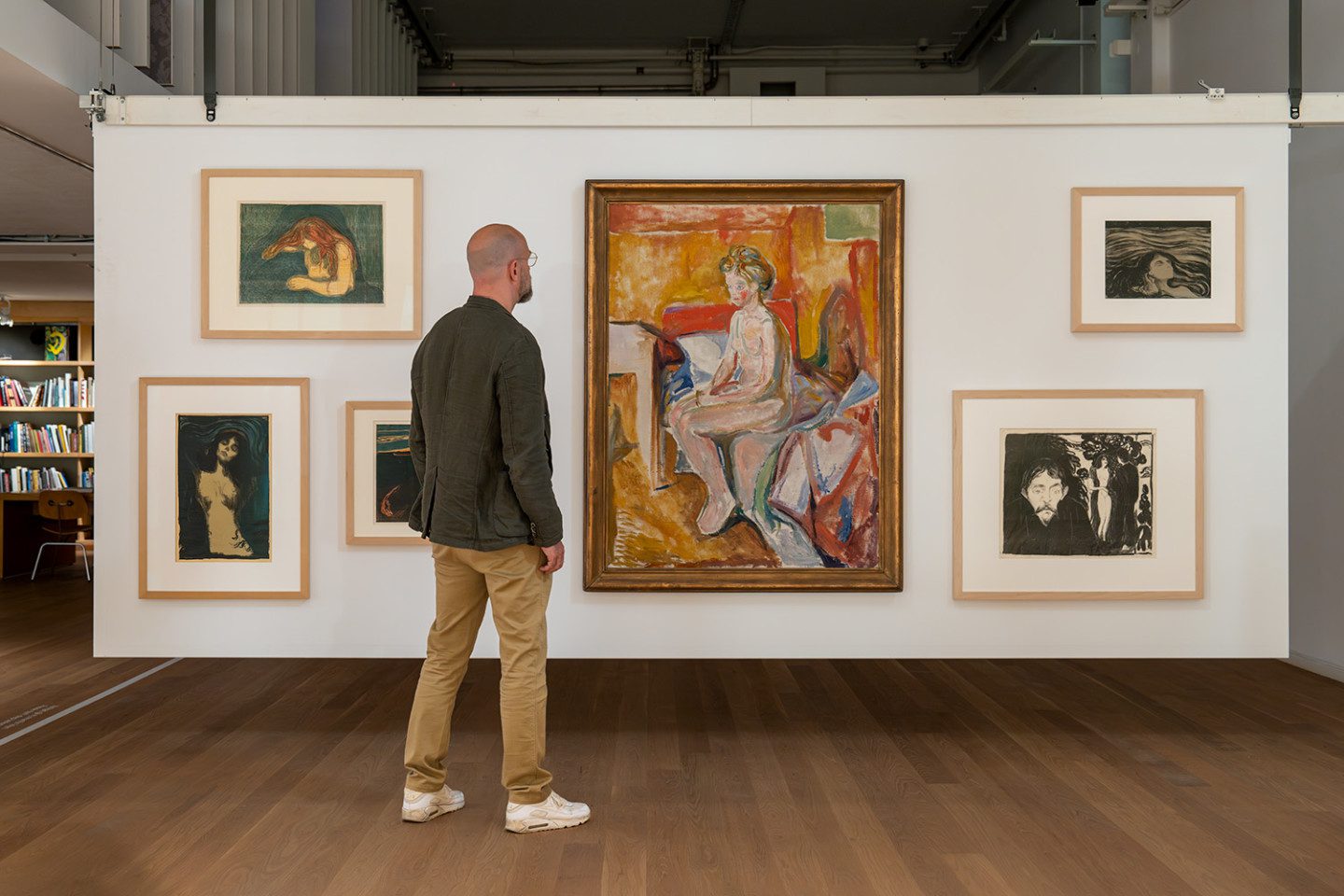 Photo of a person standing in front of one of the screens of the Study Gallery, the frame holds paintings by artist Edvard Munch