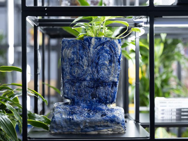 An iron grid filled with plants, lights and pottery