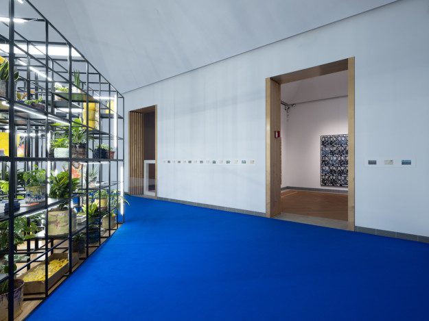An iron grid filled with plants, lights and pottery
