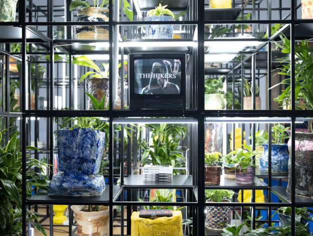 An iron grid filled with plants, lights and pottery