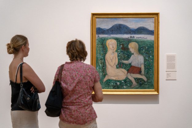 foto på två personer som står framför konstverket Barn på ängen