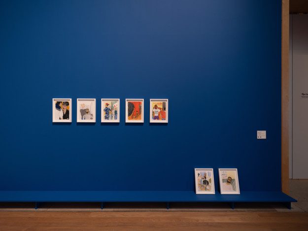 Seven sketches by the artist arranged on a blue wall