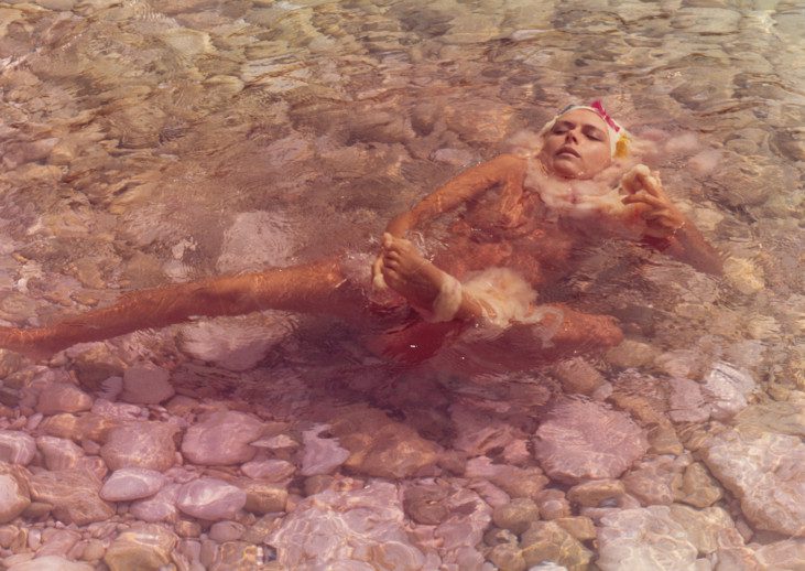 photo of person in shallow water washing their foot
