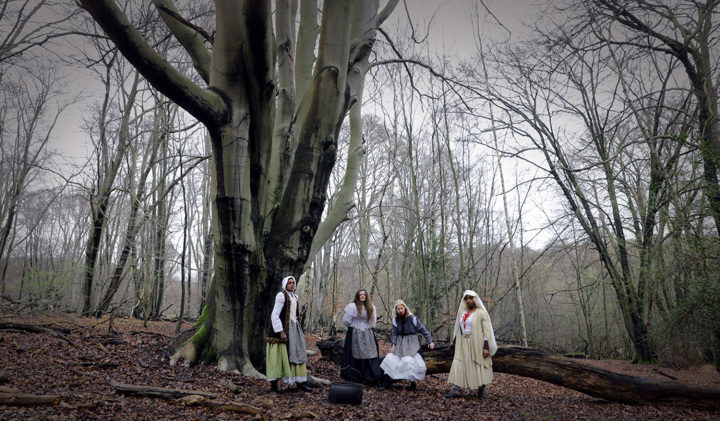 Film still from Bodily Remains, four persons standing in a forrest, one has blood around the moth and one on the chest