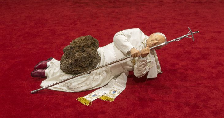 Photo of the scuplture, depicting the pope laying on his side, hit by a meteor