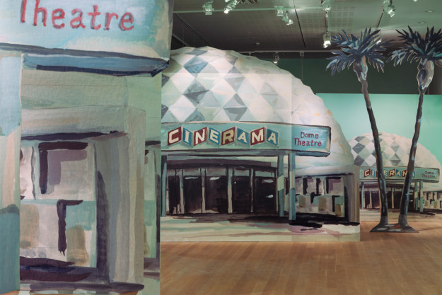 Installation view from the room "The Carla DuPlantier Cinerama Dome".  Photography of  the scenery in the exhibition: CInerama Dome Theater in Los Angeles, as well as two palm trees.