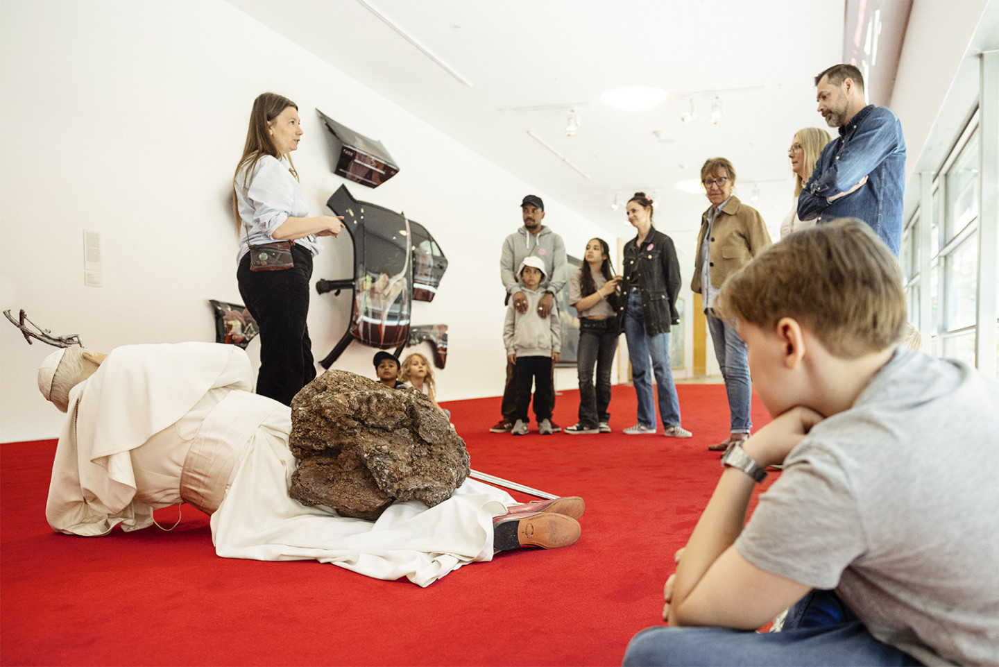 A group sees the work La Nona Ora by Maurizio Cattelan