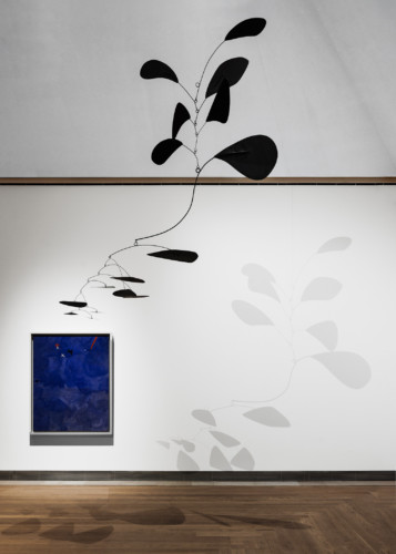 installation view with blue painting and hanging sculpture of black metal