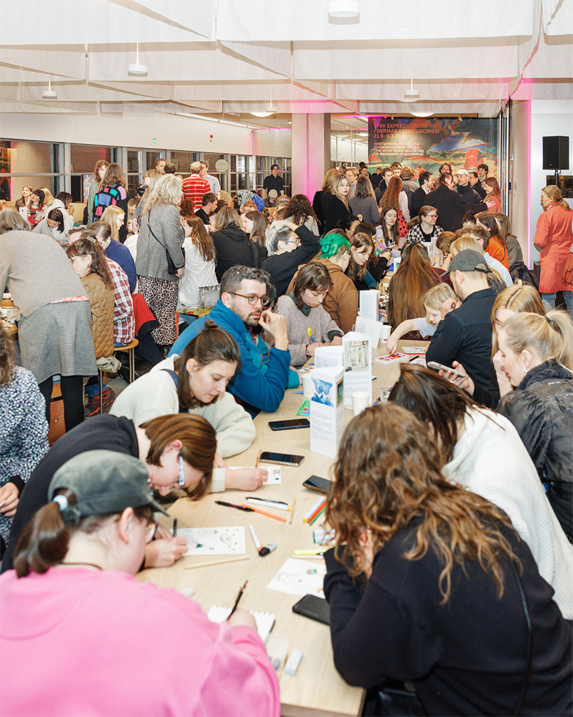 People are drawing together at a long table in the museum.