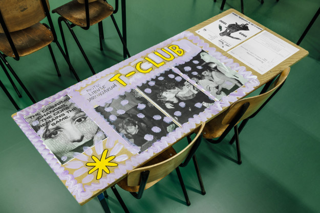 Classroom desks covered in photographs and paint